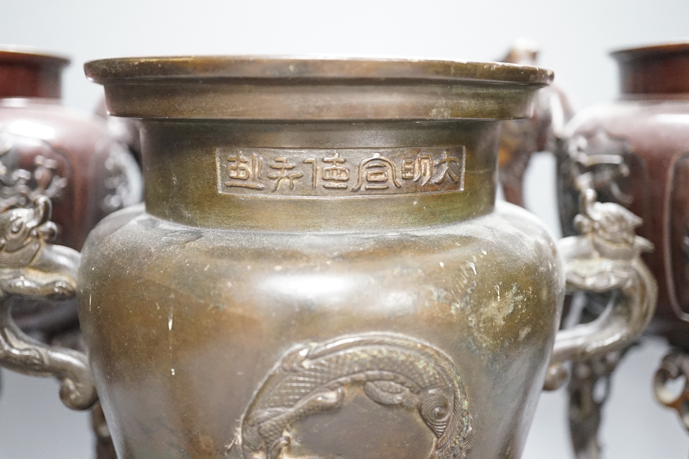 A pair of Japanese bronze vases and covers, 41 cm high and a Japanese two handled vase, 26 cm high, all Meiji period